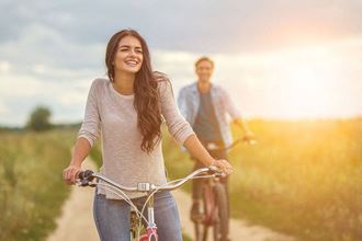 a woman riding a bike with a man in the background at Brownstones at Palisade Park Townhomes, Broomfield, 80023