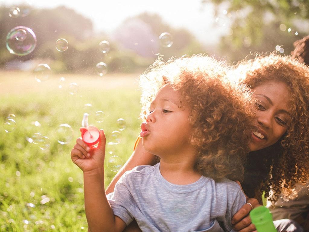a woman and child blowing bubbles in a park at Brownstones at Palisade Park Townhomes, Colorado