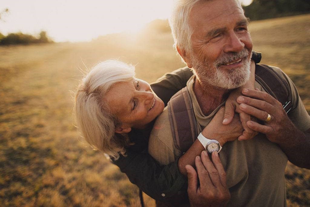 an older couple embraces in a field as the sun sets at Brownstones at Palisade Park Townhomes, Colorado, 80023
