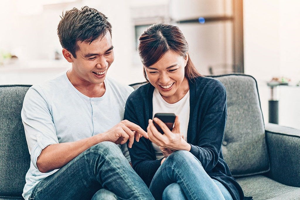 a man and woman sitting on a couch looking at a cell phone at Brownstones at Palisade Park Townhomes, Colorado