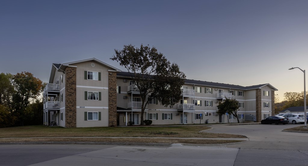 an apartment building on a street corner at dusk