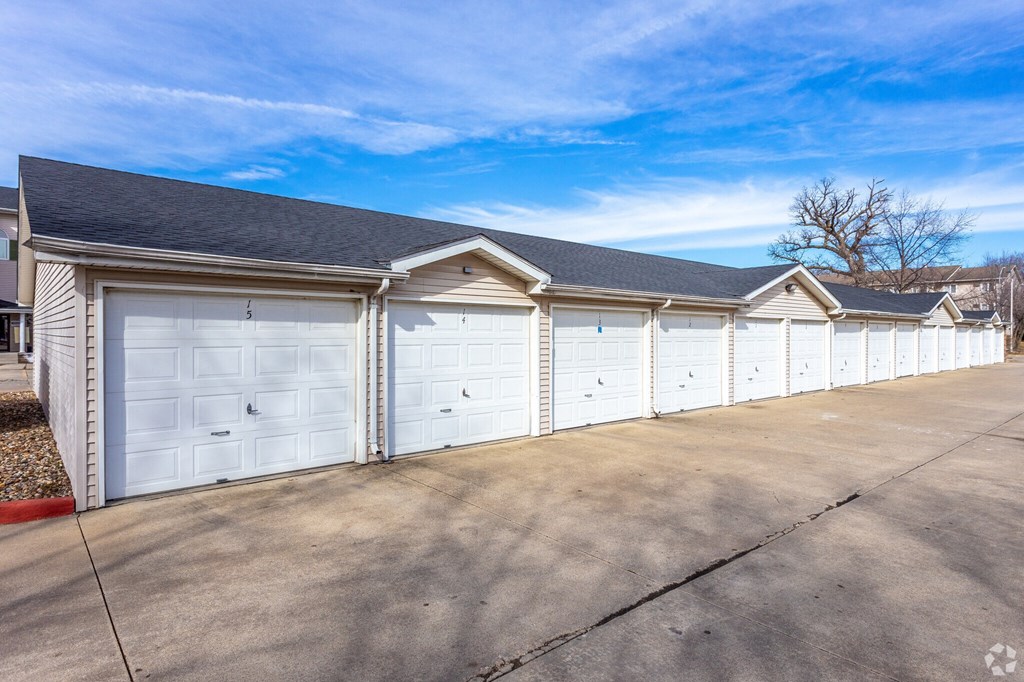 A row of white garage doors in front of a building.