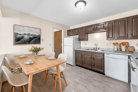 A kitchen with brown cabinets and a wooden table with chairs.