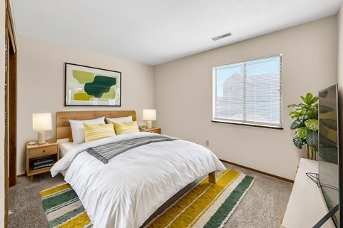 A bedroom with a bed, two lamps, a painting, and a window with blinds.