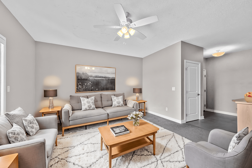 A living room with a grey couch, a coffee table, and a painting on the wall.