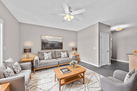 A living room with a grey couch, a coffee table, and a painting on the wall.