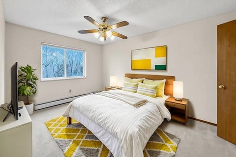A bedroom with a bed, a ceiling fan, and a window.