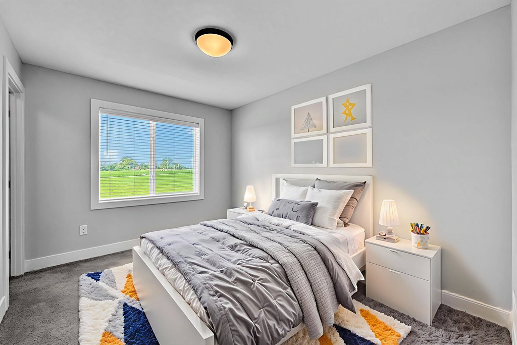 A bedroom with a large bed and a window showing a green lawn outside.