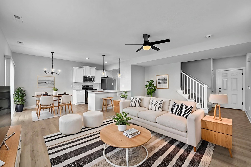 A modern living room with a white sofa, wooden coffee table, and a striped rug.