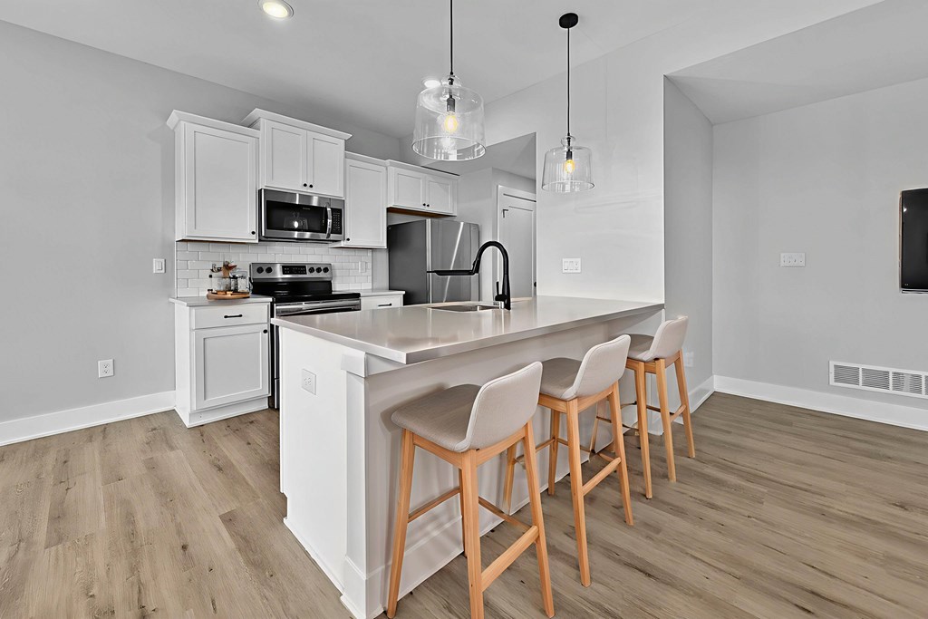 A kitchen with a white island and wooden chairs.