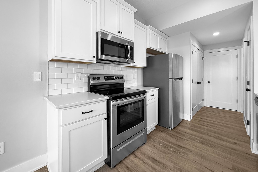 A kitchen with white cabinets and a black stove top oven.
