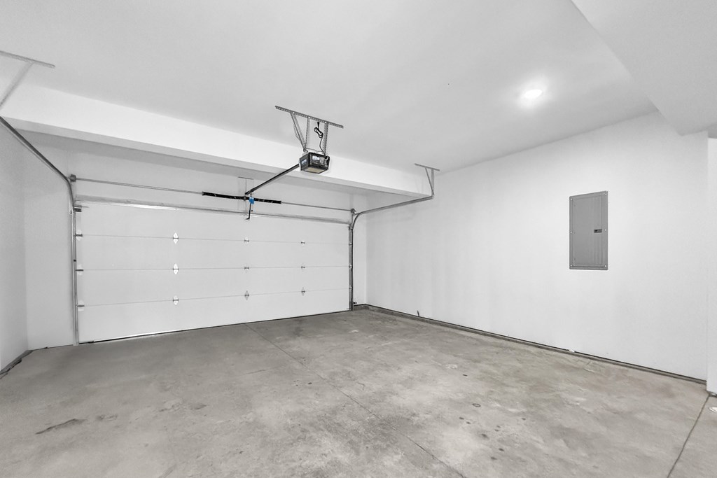 A garage with a white door and a grey floor.