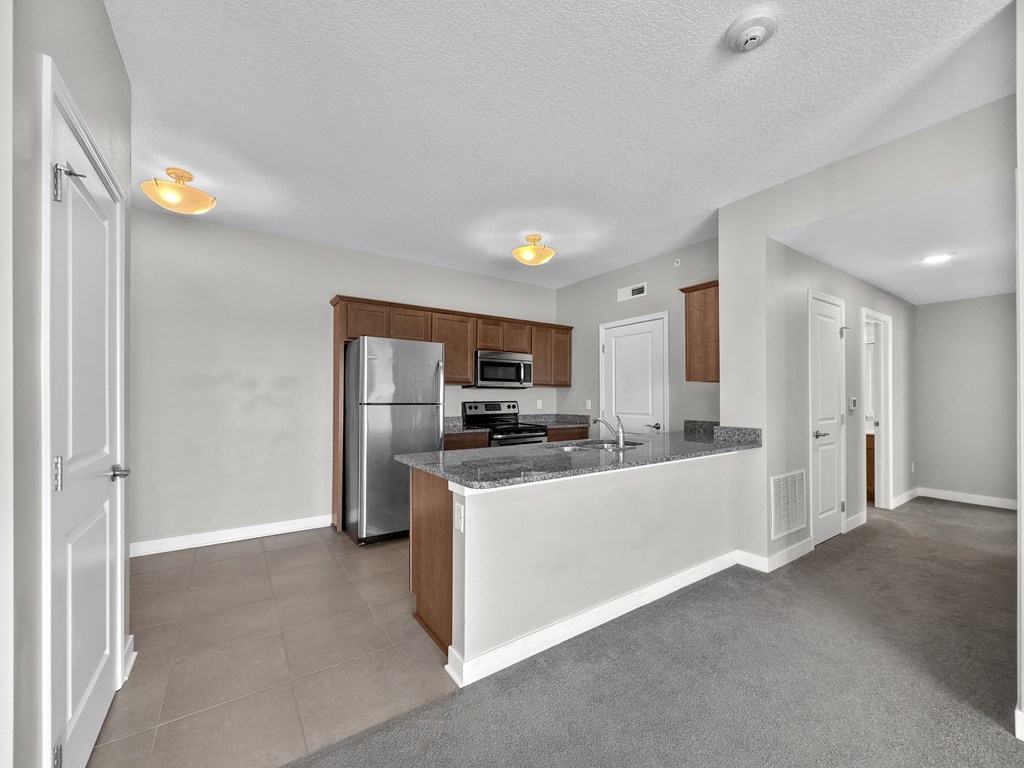 A kitchen with a refrigerator, microwave, and oven.