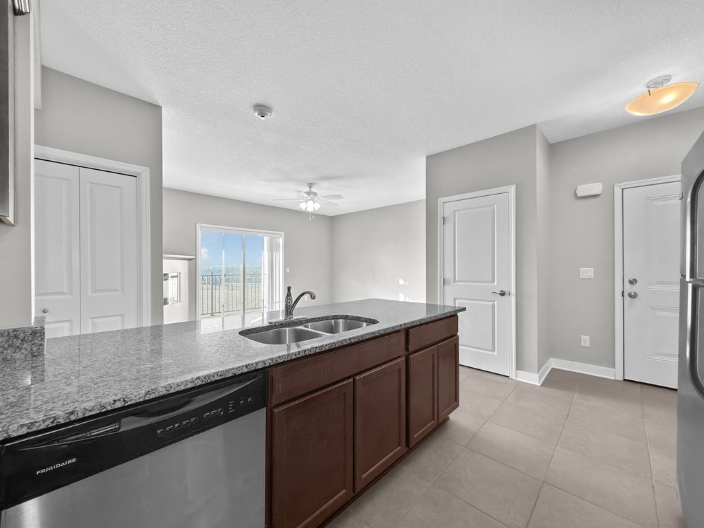 A kitchen with a black dishwasher and a granite countertop.
