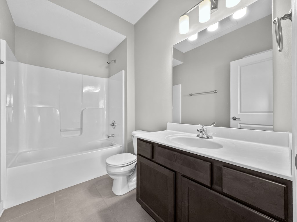 A white bathroom with a toilet, sink, and shower.
