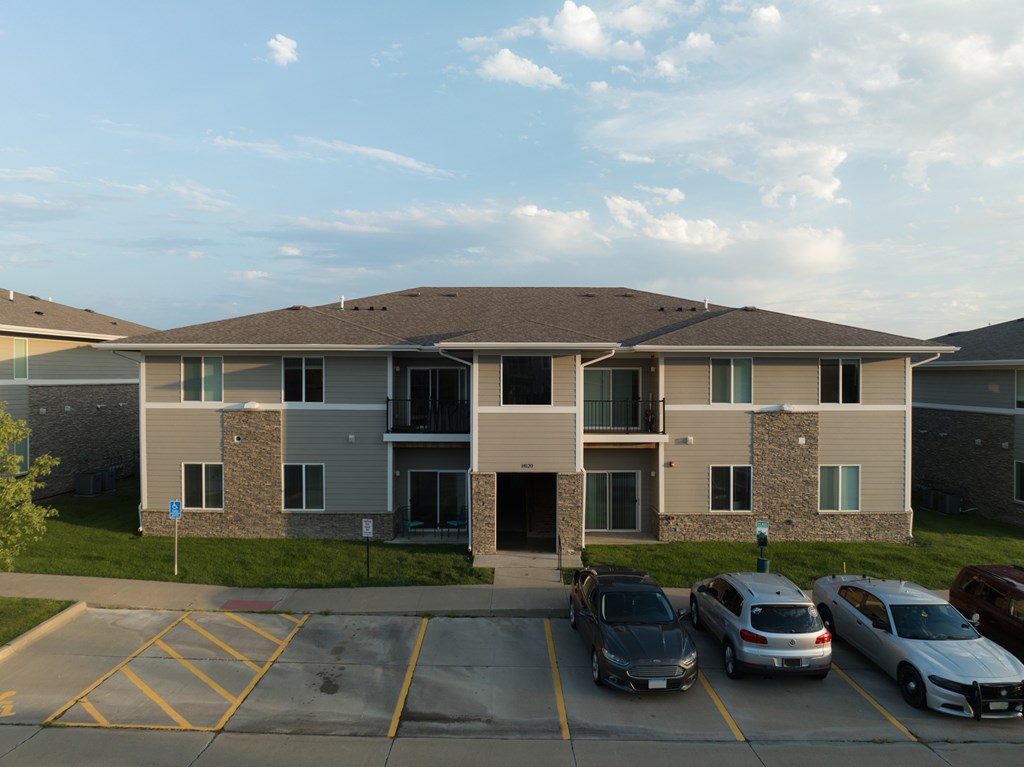 A parking lot in front of a building with cars parked.
