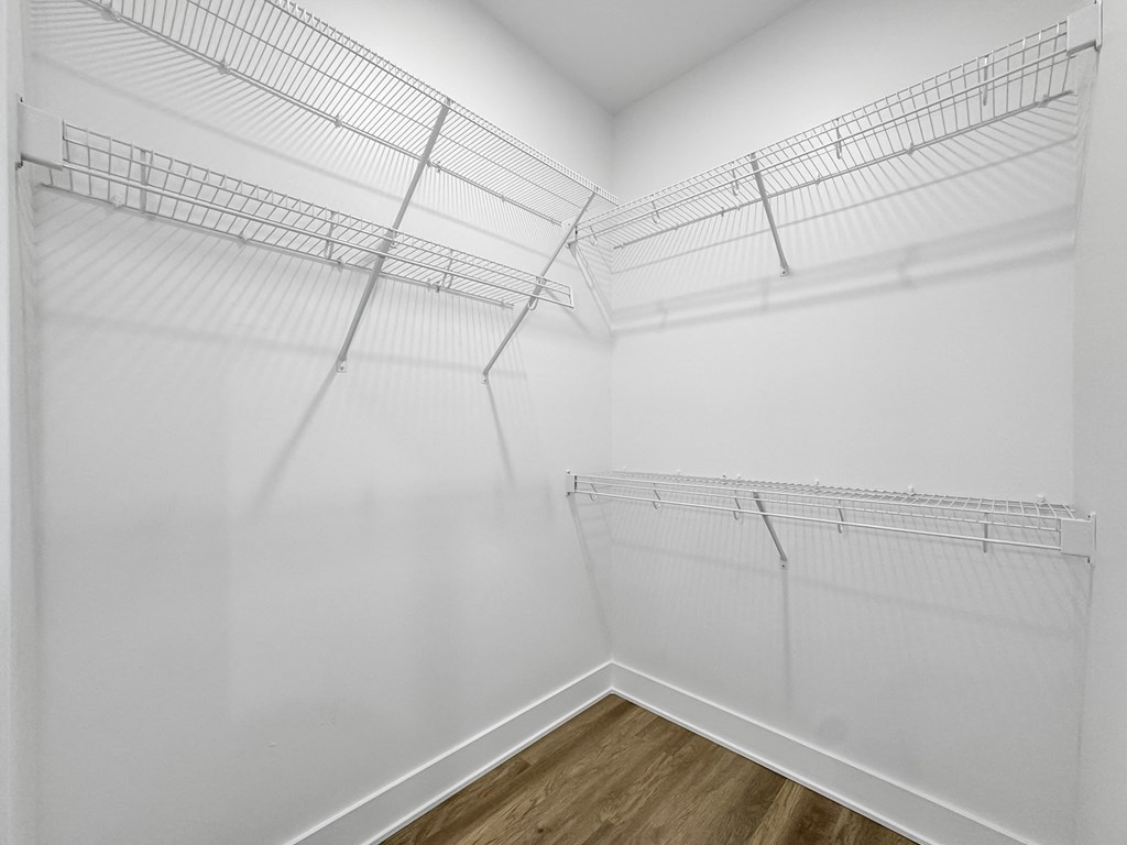 a spacious closet with white walls and wood flooring and metal racks on the wall