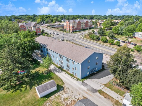 A blue building is in the foreground of a street with cars and other buildings in the background.