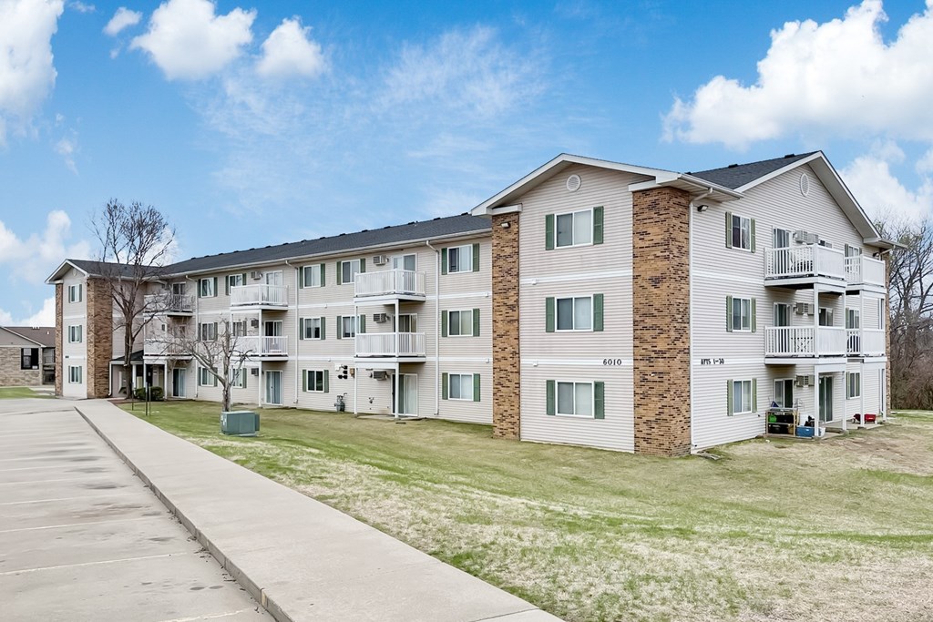 Apartment building with a parking lot in front.