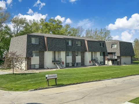 A building with a grey roof and white walls with a bench in front of it.