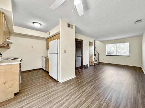 A room with a white fridge and wooden floors.