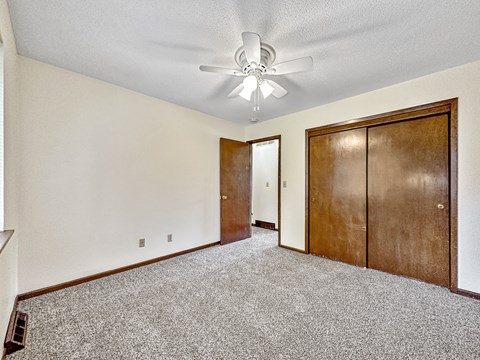 A room with a ceiling fan and two doors.