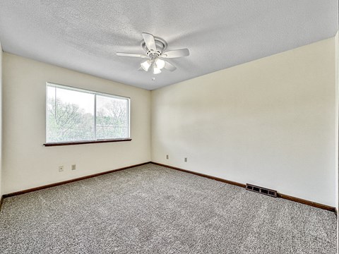 A room with a ceiling fan and a window.
