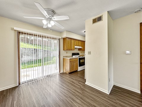 A room with a ceiling fan and sliding glass doors.