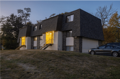 A modern house with a dark grey roof and a car parked in front.