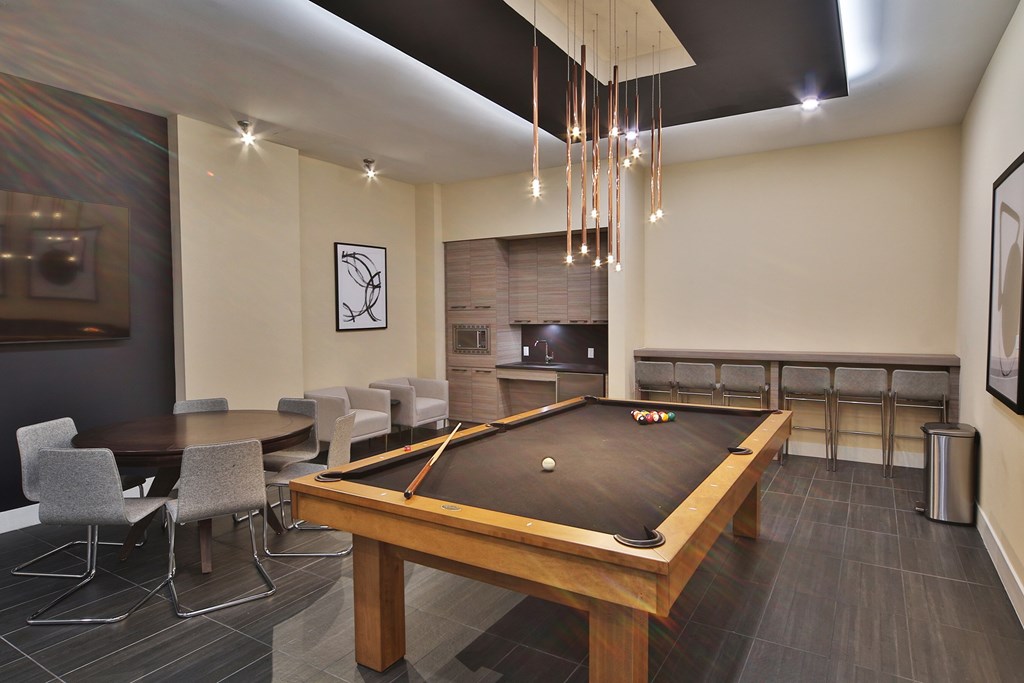 Game room with pool table, poker table, a flat screen TV, bar area and kitchenette.