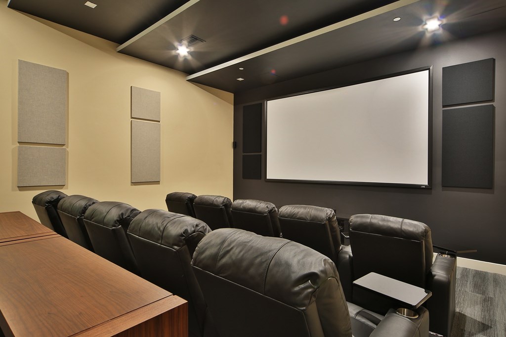 Movie theater featuring plush black reclining seats arranged in front of a large projection screen, with soundproof panels on the walls for optimal acoustics. The sleek, modern design is enhanced by soft lighting and a minimalistic layout.