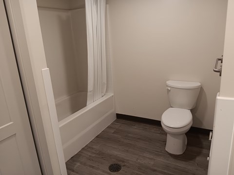 A white toilet in a small bathroom with a white shower curtain.