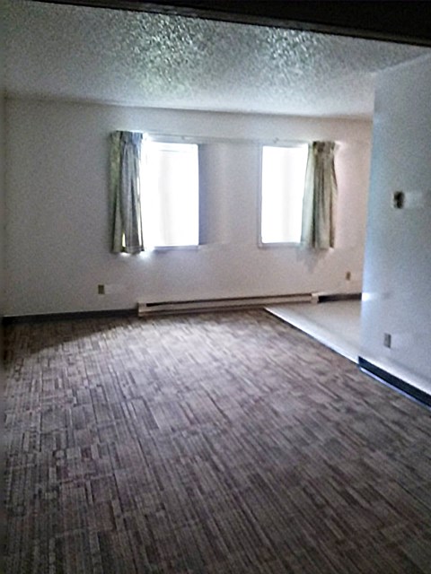 an empty living room with white walls and a wooden floor