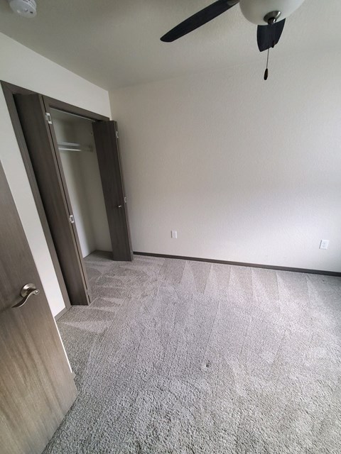 A room with a ceiling fan and a door.