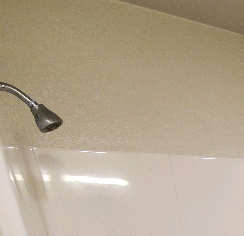A white bathtub with a shower head and a door on the side.