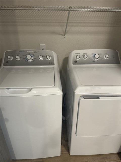 Two white front loading washing machines in a laundry room.