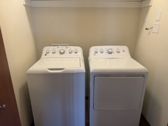 Two white front loading washing machines in a small laundry room.