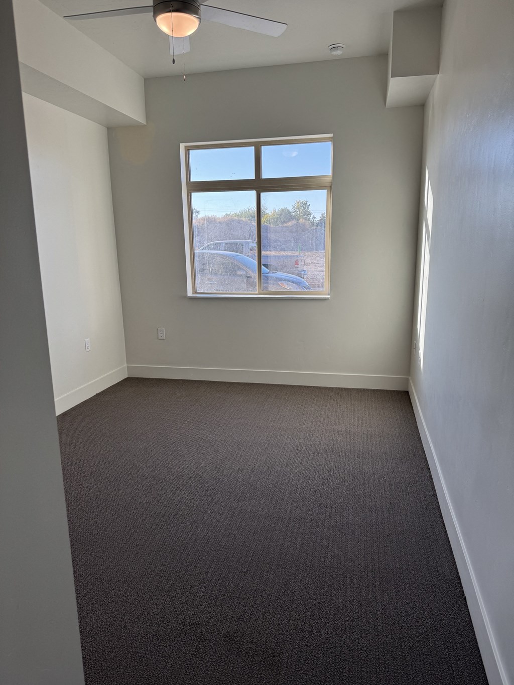 an empty bedroom with a window and a carpet