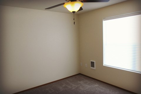 a bedroom with a ceiling fan and a large window