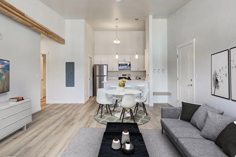 A modern living room with a grey sofa and a white dining table.