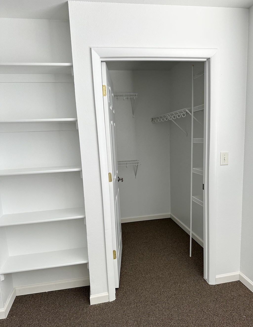 A white closet with shelves and an open door.