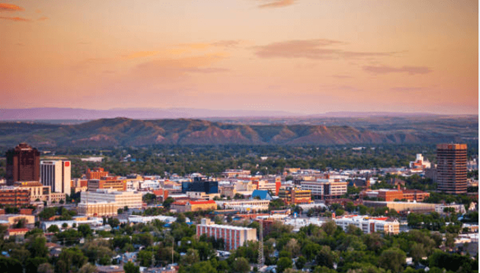 A cityscape with buildings and trees under a sunset sky.
