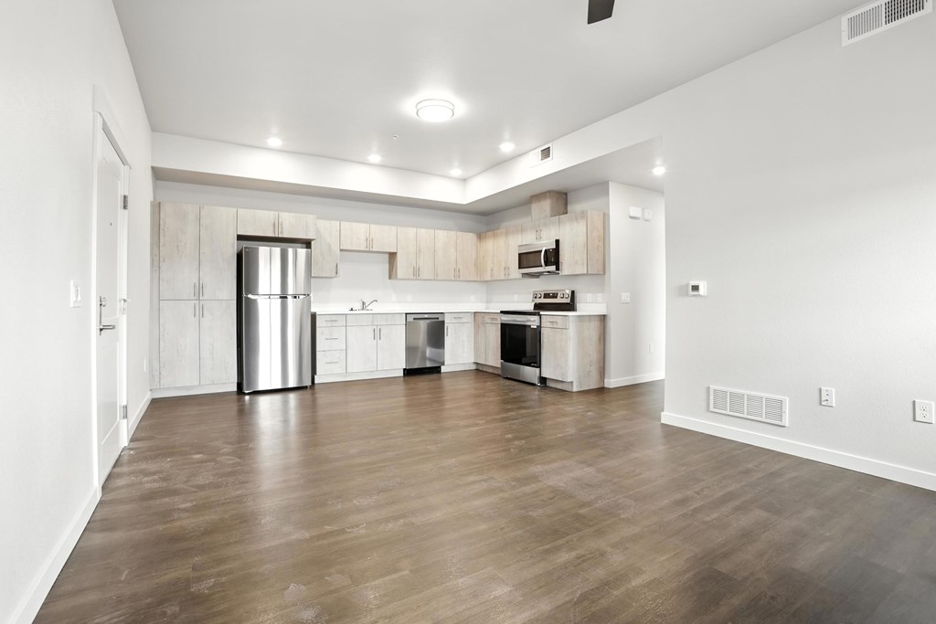A kitchen with white cabinets and a wooden floor.