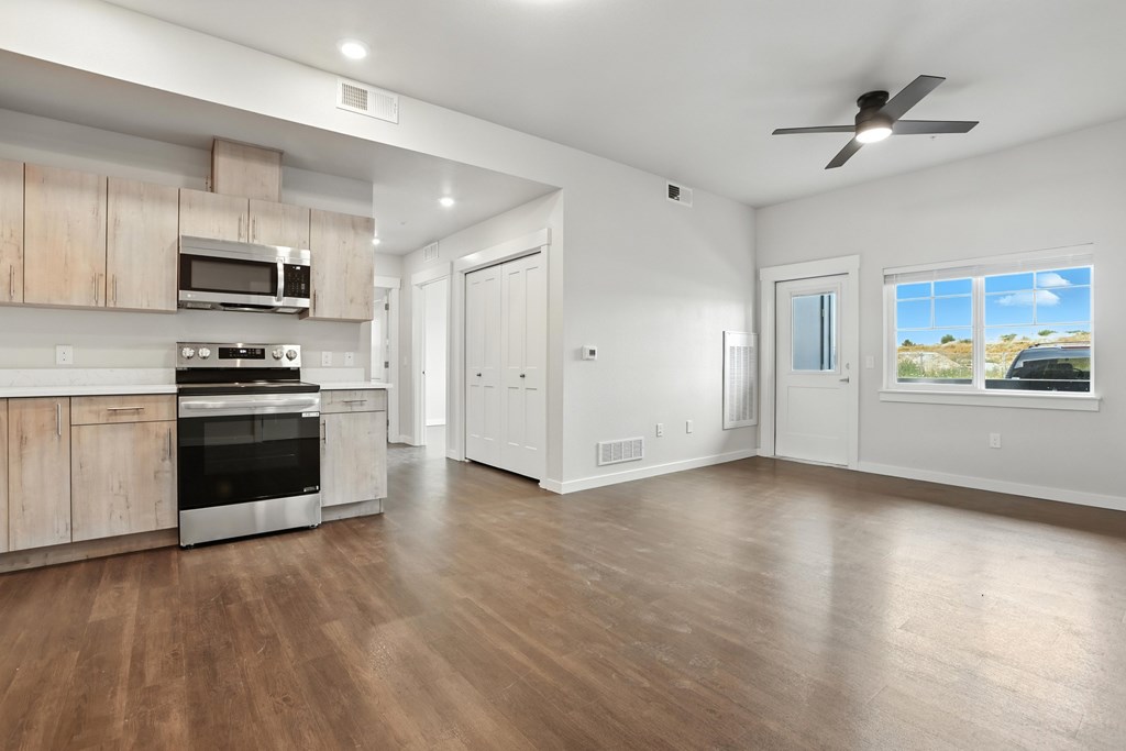 A spacious kitchen with wooden floors and a ceiling fan.