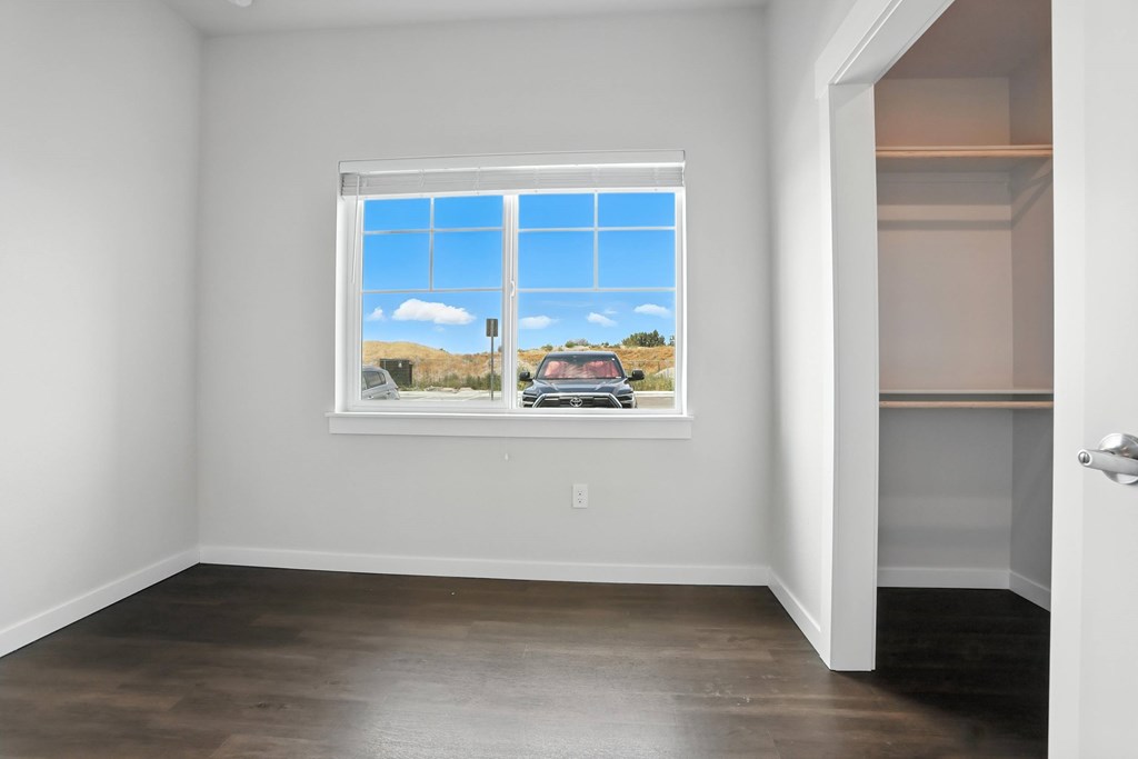 A room with a window showing a view of the sky and a car outside.