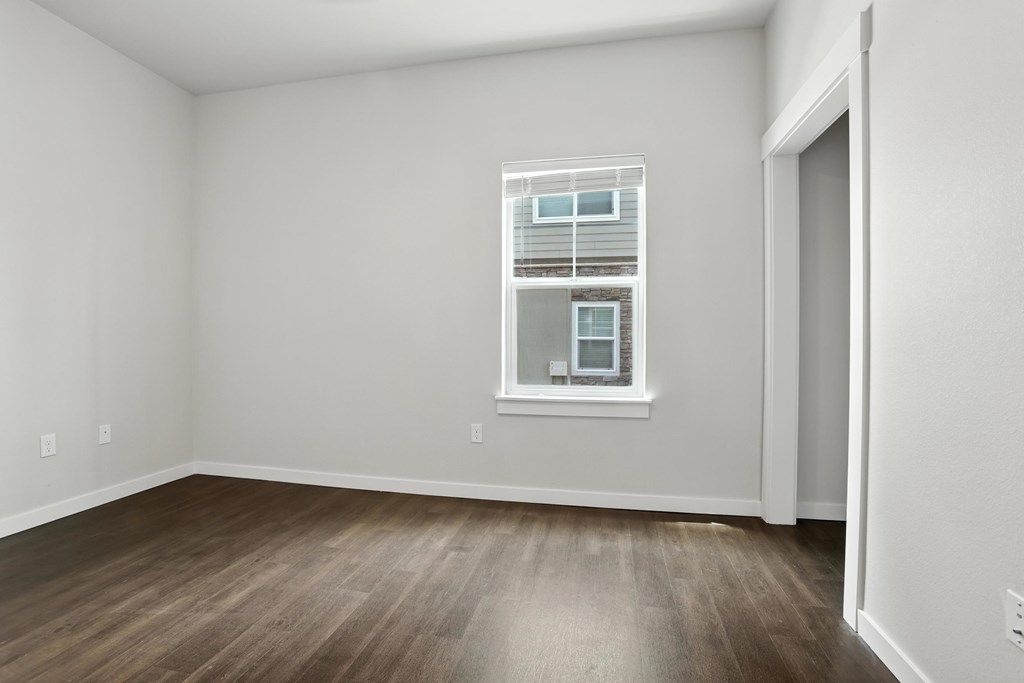 A room with a window and wooden flooring.