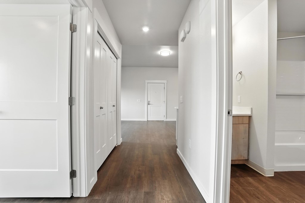 A long hallway with white doors and wood floors.