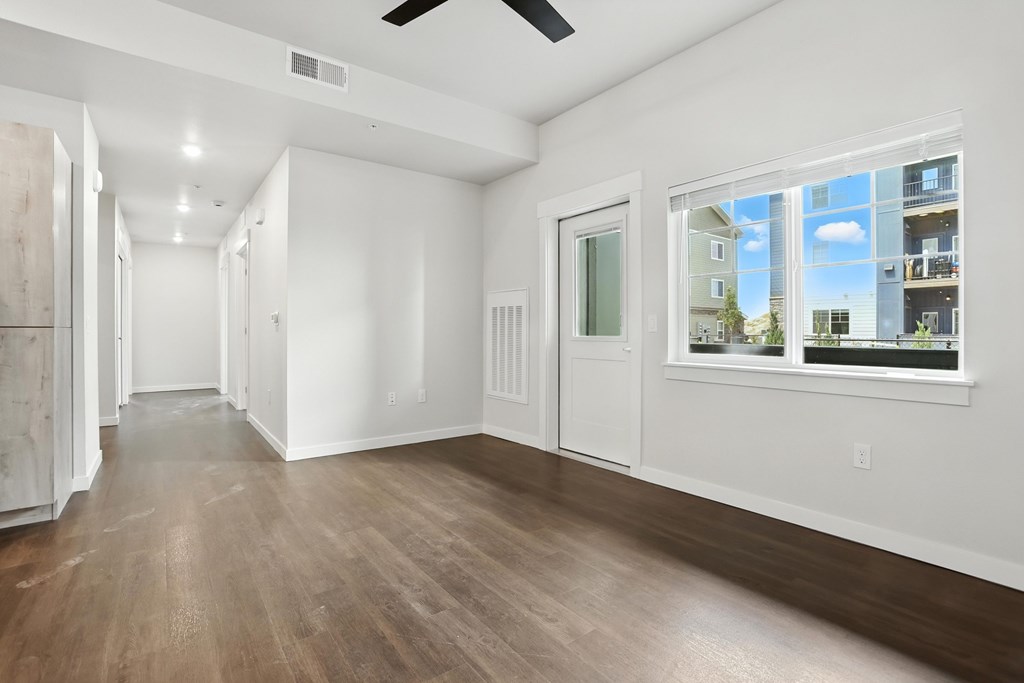 A spacious room with wooden floors and a ceiling fan.