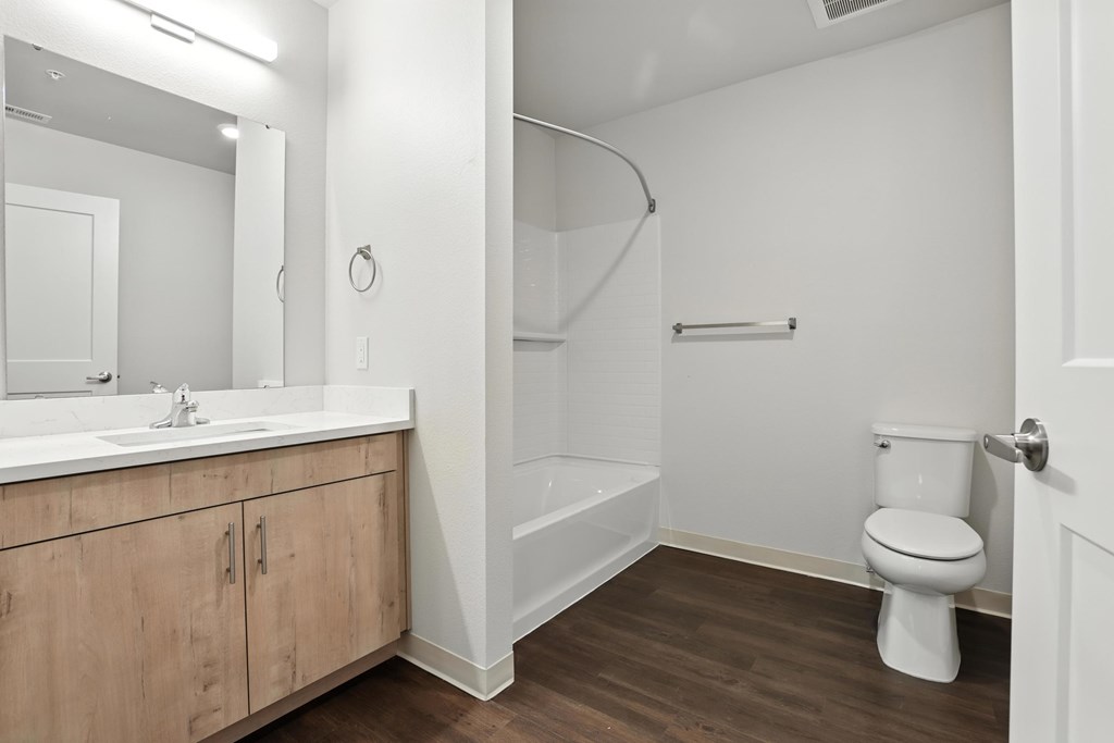 A white bathroom with a toilet, sink, and wooden cabinets.