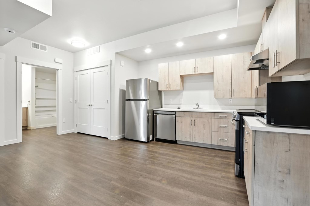 A modern kitchen with wooden floors and white cabinetry.